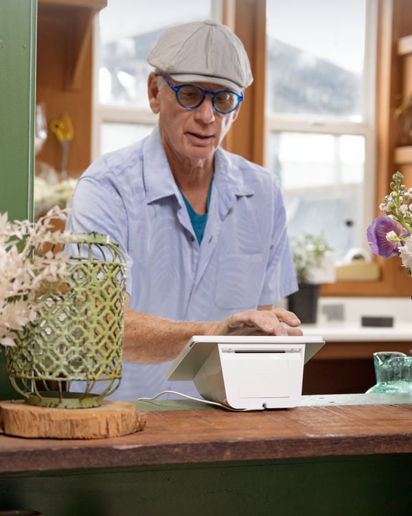 A retail store employee behind the counter using a Clover Mini A retail store employee behind the counter using a Clover Mini